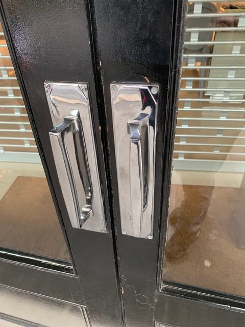 Chrome flush pull handles fitted to a black timber door