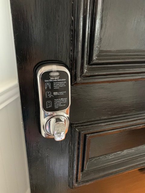 Smart lock installed on a dark timber entry door